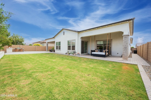 back of property with a lawn and a patio area