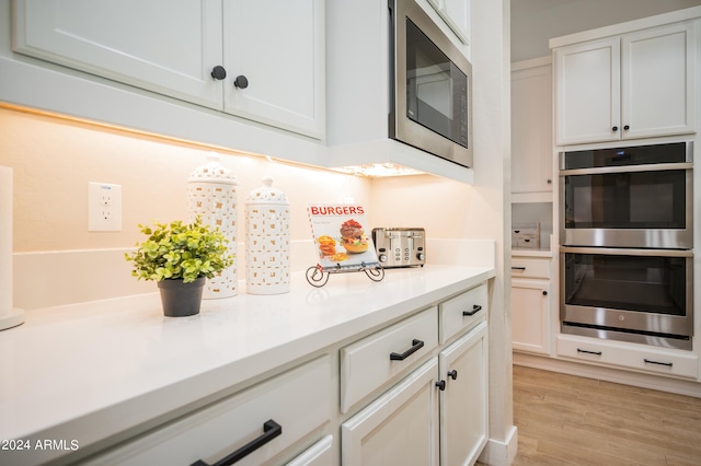 kitchen featuring white cabinets, appliances with stainless steel finishes, and light hardwood / wood-style floors