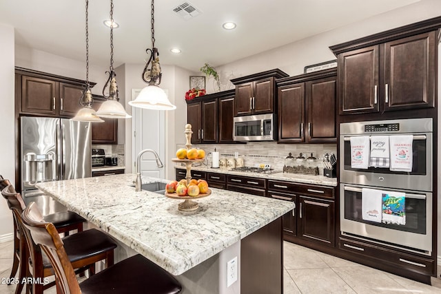 kitchen featuring visible vents, appliances with stainless steel finishes, tasteful backsplash, and a breakfast bar area