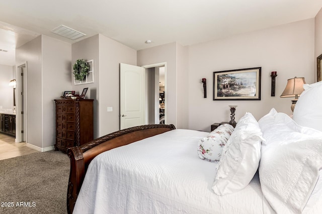 bedroom with light carpet, baseboards, visible vents, and connected bathroom