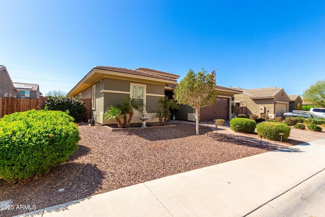 view of front of house with a garage, fence, driveway, and stucco siding