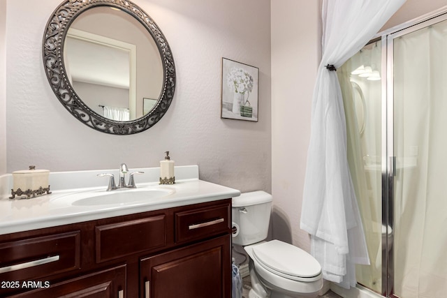 full bath featuring toilet, a stall shower, a textured wall, and vanity