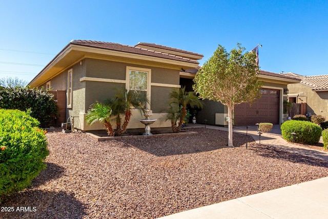 view of front of house featuring an attached garage, driveway, a tiled roof, and stucco siding