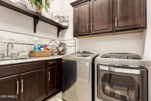 laundry room with cabinet space, light tile patterned floors, washer and clothes dryer, and a sink