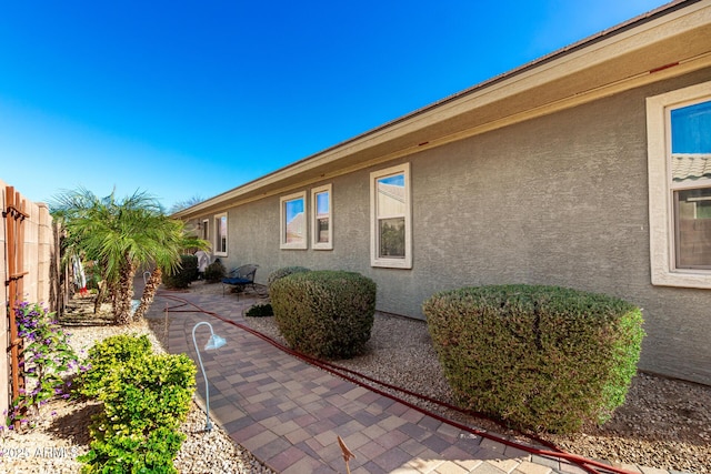 view of property exterior with a patio area, fence, and stucco siding