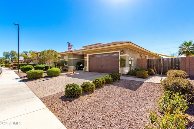 view of front of home with a garage, fence, driveway, and stucco siding