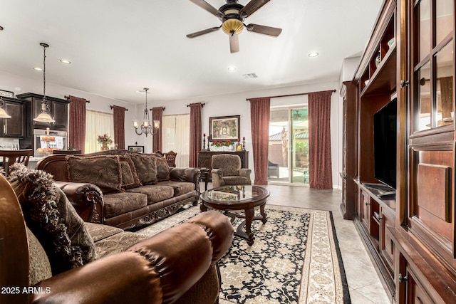 living area featuring light tile patterned flooring, visible vents, recessed lighting, and ceiling fan with notable chandelier