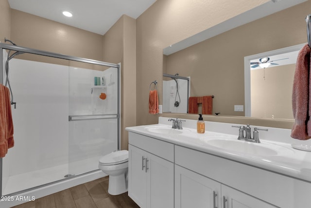 bathroom with walk in shower, toilet, wood-type flooring, vanity, and ceiling fan