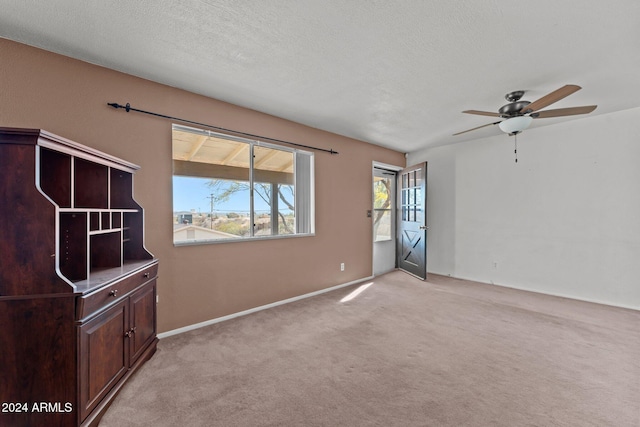 carpeted spare room with ceiling fan and a textured ceiling