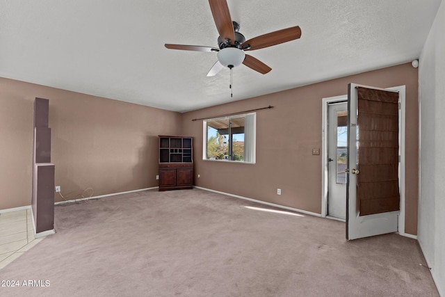 unfurnished living room featuring a textured ceiling, light colored carpet, and ceiling fan