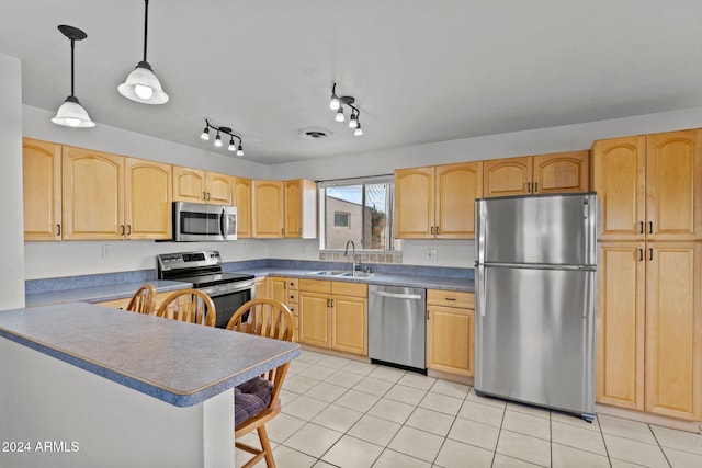 kitchen featuring kitchen peninsula, appliances with stainless steel finishes, light brown cabinetry, sink, and hanging light fixtures