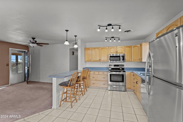 kitchen with light carpet, appliances with stainless steel finishes, pendant lighting, and light brown cabinetry