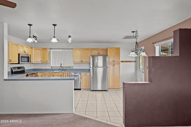 kitchen featuring sink, kitchen peninsula, pendant lighting, light tile patterned floors, and appliances with stainless steel finishes