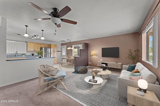 living room with light carpet, ceiling fan with notable chandelier, and sink