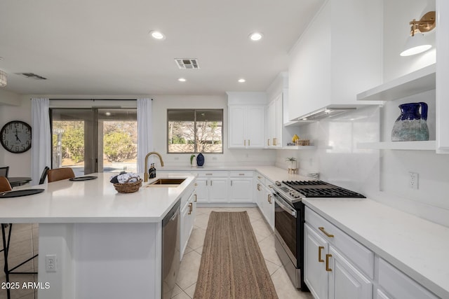 kitchen with a kitchen island with sink, white cabinets, appliances with stainless steel finishes, and a kitchen breakfast bar