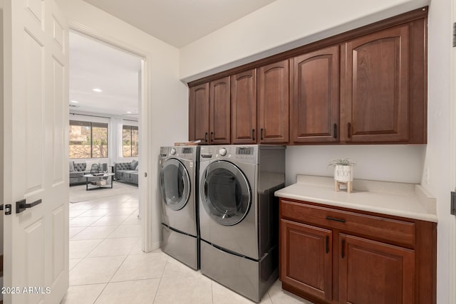 clothes washing area featuring light tile patterned floors, cabinets, and independent washer and dryer