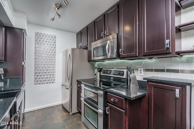 kitchen featuring backsplash, stone finish flooring, dark brown cabinetry, dark stone counters, and stainless steel appliances