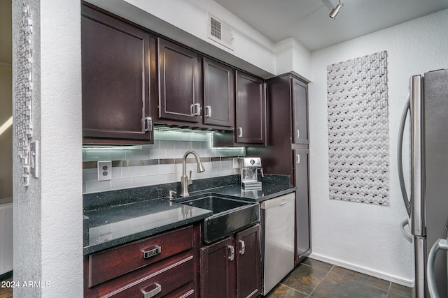 kitchen with a sink, backsplash, freestanding refrigerator, dark stone counters, and dishwasher