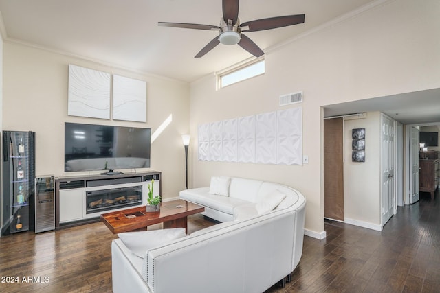 living area featuring visible vents, dark wood-type flooring, ornamental molding, a glass covered fireplace, and baseboards