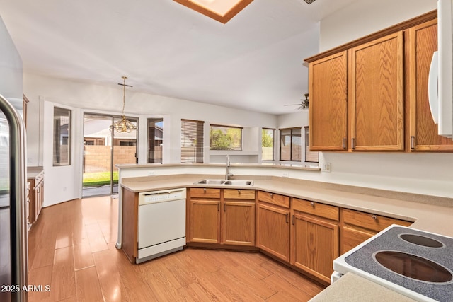 kitchen with a sink, light countertops, a peninsula, and white appliances