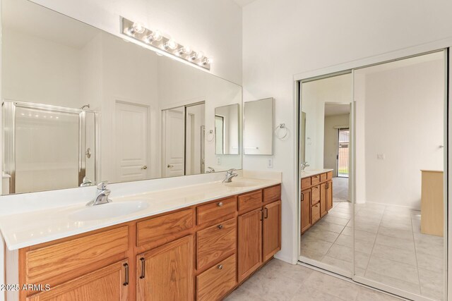 full bath featuring double vanity, walk in shower, a sink, and tile patterned flooring