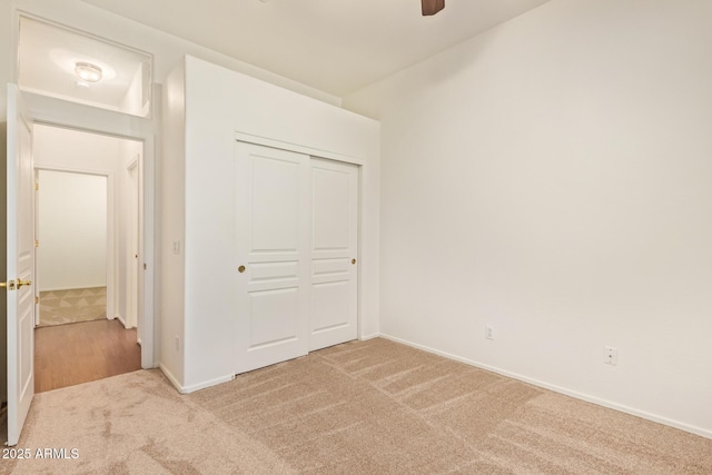 unfurnished bedroom featuring a closet, carpet, ceiling fan, and baseboards