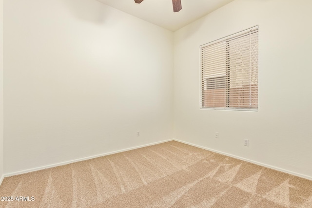 carpeted spare room featuring baseboards and ceiling fan