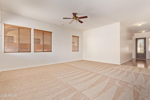 carpeted empty room featuring baseboards, a ceiling fan, and visible vents