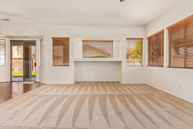 unfurnished living room featuring carpet floors, baseboards, and visible vents