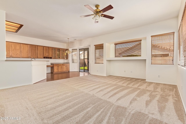unfurnished living room featuring baseboards, carpet flooring, and a ceiling fan