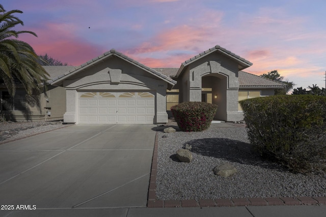 mediterranean / spanish-style house featuring a garage, concrete driveway, a tile roof, and stucco siding