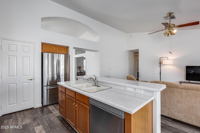 kitchen featuring lofted ceiling, a sink, open floor plan, appliances with stainless steel finishes, and dark wood finished floors