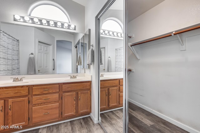 full bath with wood finished floors, a sink, baseboards, and double vanity