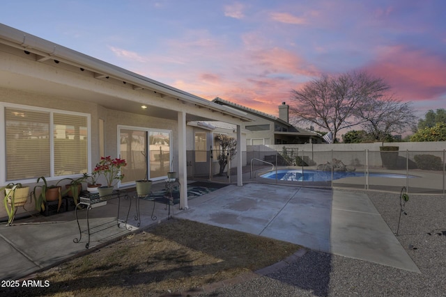 pool at dusk with a patio area, a fenced backyard, and a fenced in pool