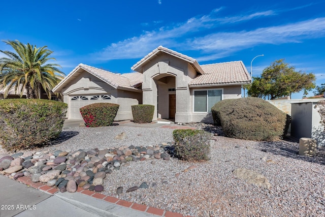 ranch-style home with a tiled roof, an attached garage, and stucco siding