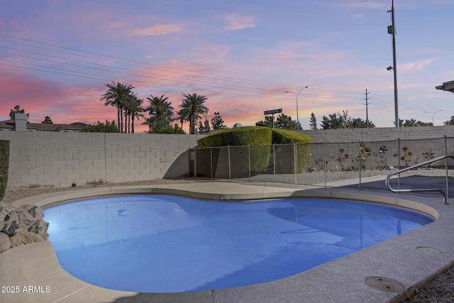 pool at dusk featuring a fenced backyard and a fenced in pool