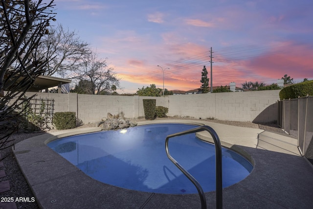 pool at dusk featuring a fenced backyard and a fenced in pool