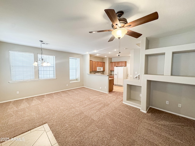 unfurnished living room with ceiling fan with notable chandelier, light colored carpet, and built in features