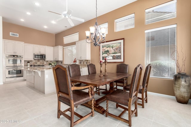 dining area featuring light tile patterned flooring and ceiling fan with notable chandelier