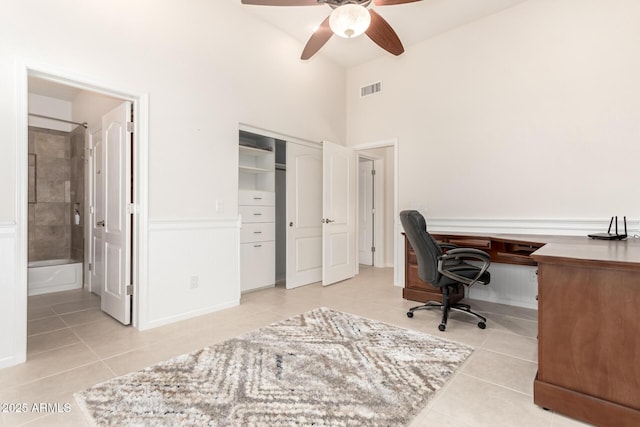 office area with ceiling fan, light tile patterned floors, and a towering ceiling