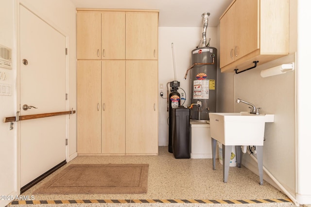 clothes washing area with cabinets and water heater