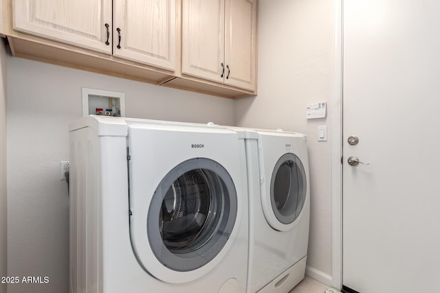 clothes washing area featuring cabinets and independent washer and dryer