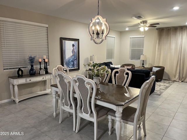 tiled dining space with ceiling fan with notable chandelier