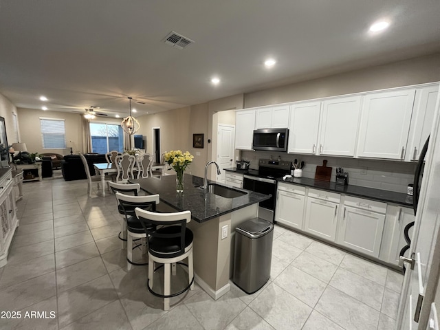 kitchen featuring sink, decorative light fixtures, appliances with stainless steel finishes, an island with sink, and white cabinets