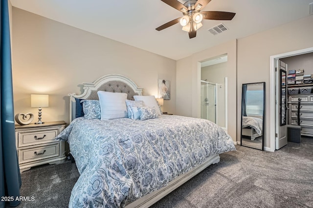 bedroom featuring ceiling fan, ensuite bath, and dark colored carpet