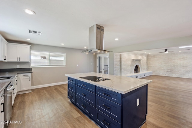 kitchen with black electric stovetop, a center island, white cabinets, brick wall, and ventilation hood