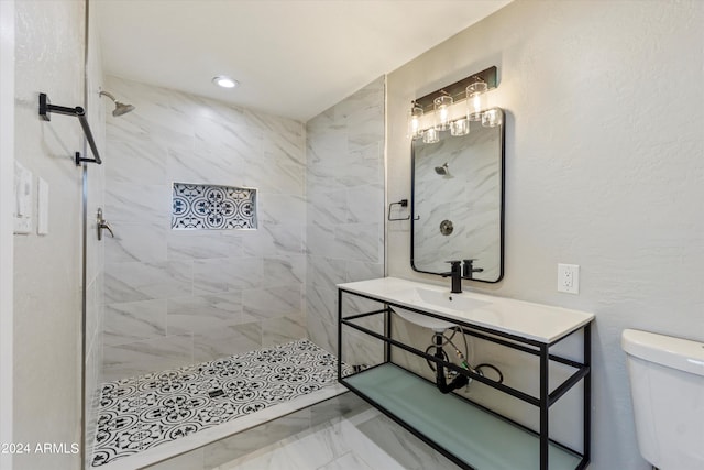 bathroom with vanity, tiled shower, and toilet