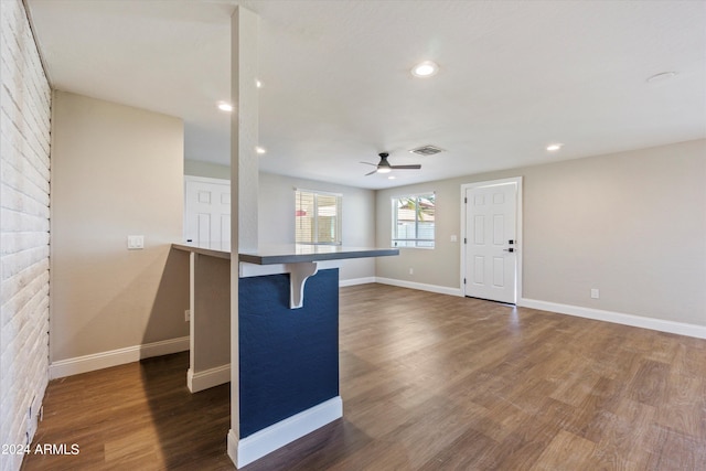 kitchen with a kitchen breakfast bar, kitchen peninsula, ceiling fan, and dark hardwood / wood-style flooring