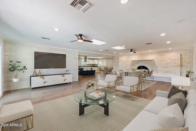 living room featuring light hardwood / wood-style flooring, brick wall, and ceiling fan