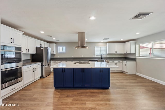 kitchen featuring white cabinets, island range hood, light hardwood / wood-style flooring, stainless steel appliances, and a center island